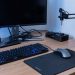 Bureau compact et bien organisé avec clavier mécanique fin, souris gaming, support de casque, tapis de bureau, gestion des câbles et bras de moniteur.