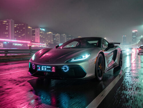 Vue nocturne cinématographique d’une voiture sportive roulant dans une ville côtière illuminée par des néons roses et cyan, avec des reflets sur la chaussée mouillée.